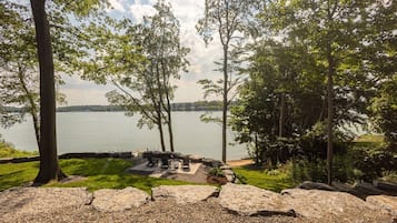 A lakeside outdoor seating area with stone benches and a fire pit.
