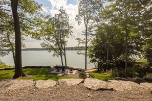 Un espacio al aire libre junto al lago con bancos de piedra y un hogar para fogata.