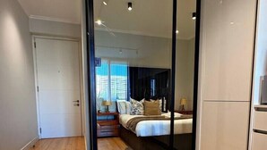 Un dormitorio con cama, mesitas de noche, armario y espejo.