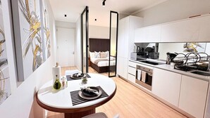 Una habitación de hotel moderna con comedor, kitchenette y una cama con vistas.