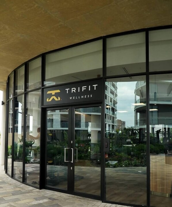 A modern building with a glass facade and a sign reading 'TRIPIT WELLNESS'. - Elite Executive Suite | Ellipse | Waterfall City (Midrand)