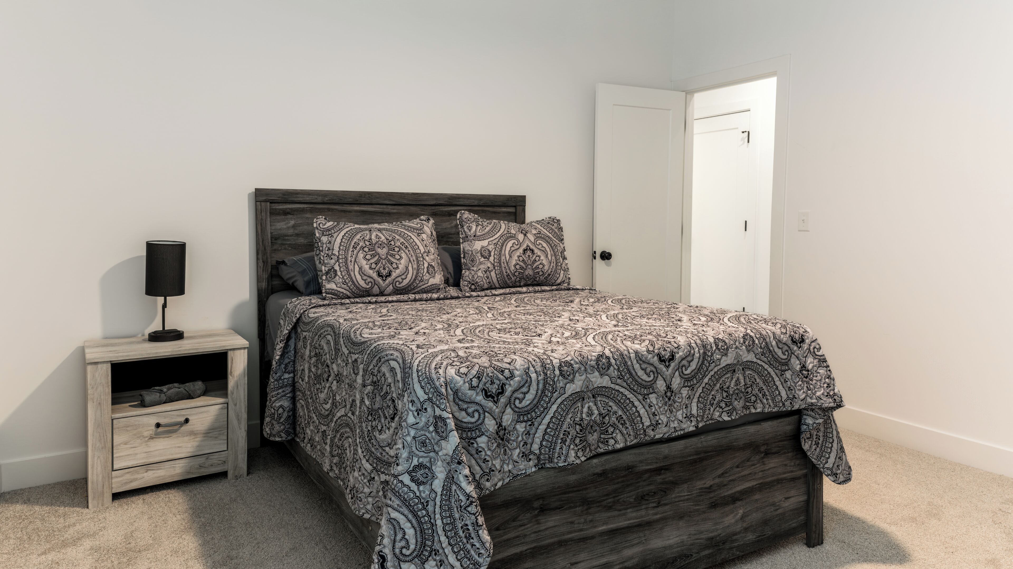 A bedroom with a bed, nightstand, and a door.