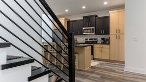 Una cocina moderna con armarios negros y de madera, un microondas de acero inoxidable y una isla de madera.