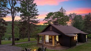 Un chalet rustique doté d’une véranda, d’un espace salon extérieur et d’un foyer.