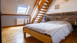 A bedroom with a wooden ceiling, a bed, a window, and a radiator.
