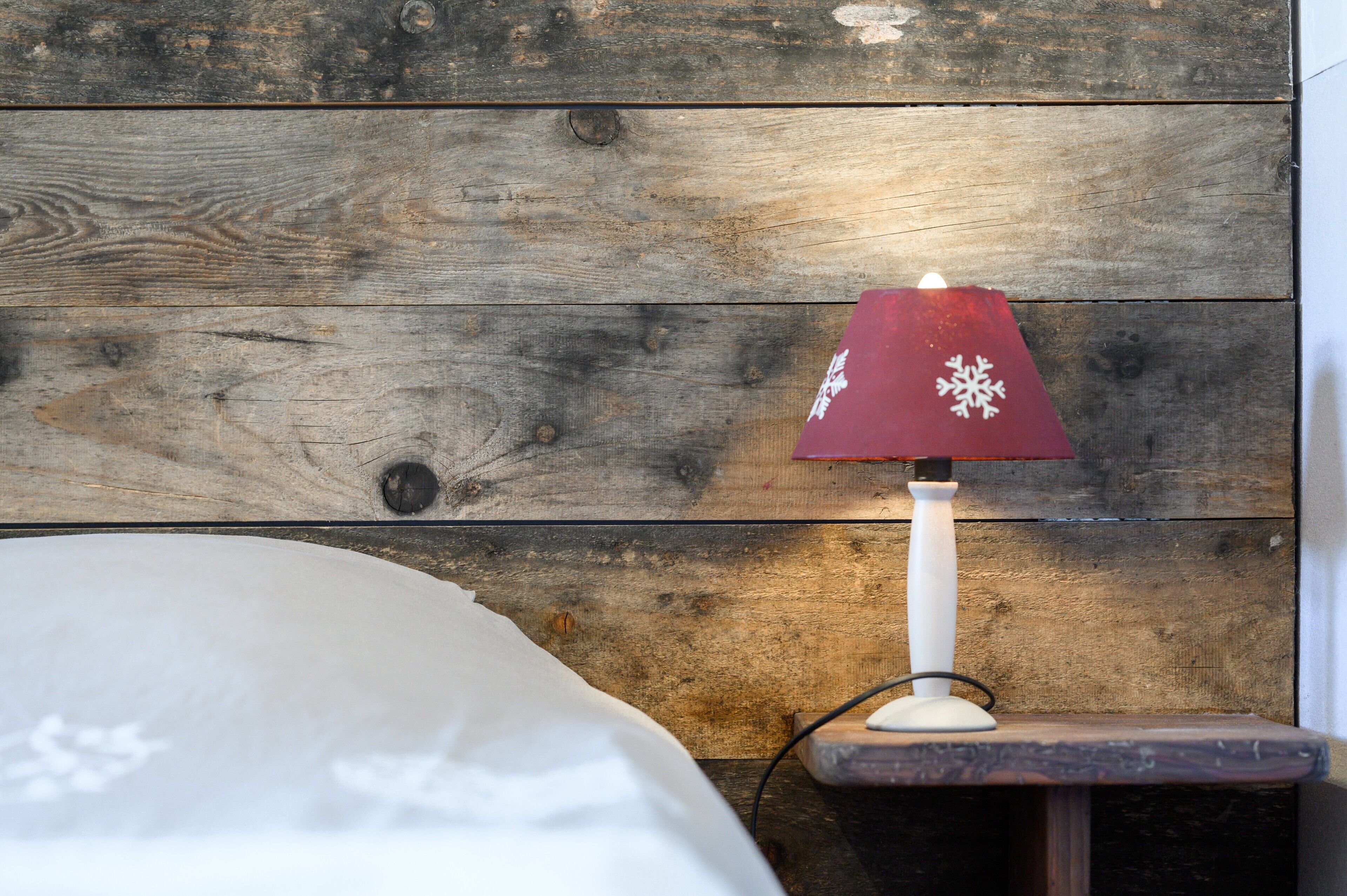 A wooden wall with a white lamp on a small table.