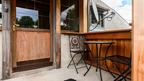 A wooden door, a metal chair, and a small table outside a building. - Guest House 'Suite Familiale - Kobo-Maya' with Mountain View and Shared Garden (Orbey)