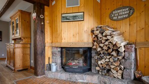 A wooden interior with a fireplace, a sign reading 'Bienvenue A La Ferme Du Racou,' and a framed picture on the wall. - Guest House 'Suite Familiale - Kobo-Maya' with Mountain View and Shared Garden (Orbey)
