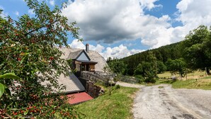 A house with a stone exterior, a red roof, and a wooden fence. - Guest House 'Suite Familiale - Kobo-Maya' with Mountain View and Shared Garden (Orbey)