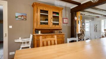 Un coin repas comprenant une table en bois, des chaises, un buffet aux portes vitrées et un tableau accroché au mur.