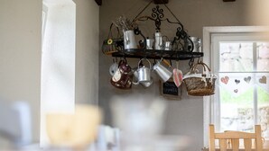 A kitchen with hanging pots and pans, a wooden bench, and a window with a view. - Guest House 'Suite Familiale - Kobo-Maya' with Mountain View and Shared Garden (Orbey)