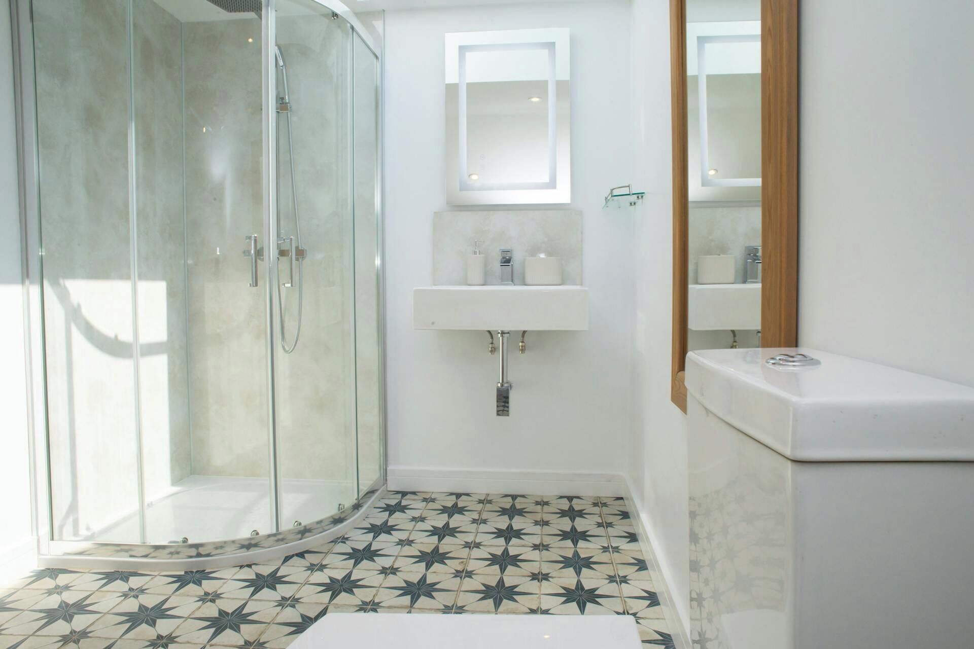 A bathroom with a glass shower enclosure, a white sink, and a mirror.
