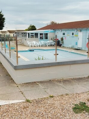 A pool area with a cafe named 'COAST CAFE' in the background. - Stay 6 - Pool - Parking - Beachside - Pet Friendly (Norwich)