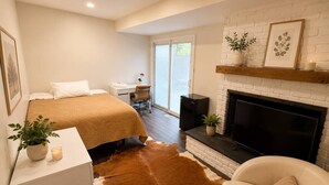 Une chambre moderne avec un lit, une cheminée, un téléviseur et un bureau.