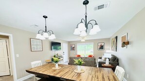 A dining area with a wooden table, white chairs, a bench, and a ceiling fan. - Beautiful Eastgate 12B (Hammond)