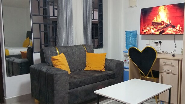 Un salón con sofá, una mesita, un televisor mostrando un fuego y un espejo.