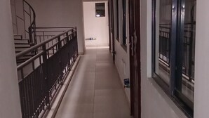 Un pasillo con suelo de baldosas, una escalera a la izquierda y una puerta a la derecha.
