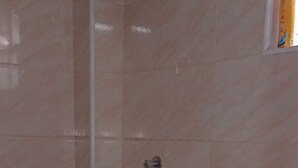 Un baño con inodoro, ducha y un tapete pequeño.