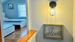 Un dormitorio con cama, mesita de noche y lámpara fijada a la pared.