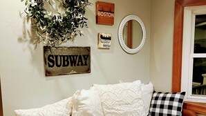 Una sala de estar acogedora con un sofá, decoración en la pared y suelo de madera.