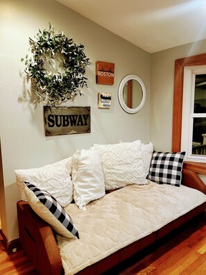 A cozy living room with a sofa, decorative wall art, and a wooden floor.