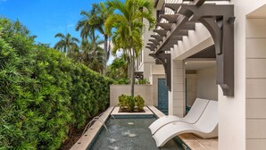 Ein Pool mit Rutsche, umgeben von üppiger Bepflanzung und einem modernen Gebäude mit Balkon.