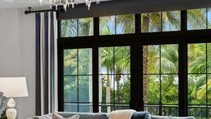Ein modernes Wohnzimmer mit Ecksofa, Hocker und einer Chandelier.