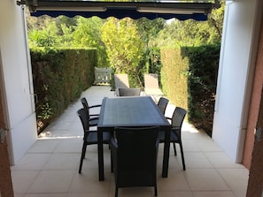 An outdoor patio with a table and chairs, surrounded by greenery and a white wall. - Rent beautiful duplex near Le Lavandou only from 11 to 18 /07 and after 22 08 (le lavandou)