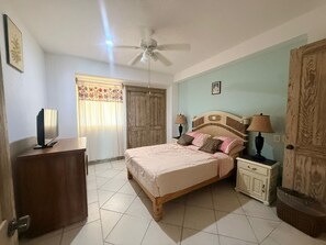 A bedroom with a bed, bedside tables, a ceiling fan, and a wardrobe. - Oceanfront Condo at Bay View Grand | Infinity Pool, Gym, and Tennis Court (Puerto Vallarta)