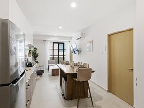 Eine moderne Küche mit Kühlschrank, eine Essecke mit Tisch und Stühlen sowie eine Holztür.