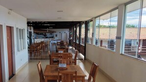 A corridor with wooden tables and chairs, a sign indicating a reserved suite, and a view of the outside through large windows. - Suíte com Jacuzzi Vista de Escarpas 1 (Capitólio)