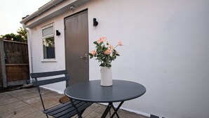 Eine Terrasse mit einem runden Tisch, zwei Bänken und einem Blumentopf.
