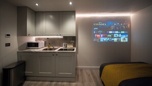 Eine moderne Küche mit Einbau-Mikrowelle, Toaster und Spüle, sowie eine Projektionsleinwand, die einen Film zeigt.