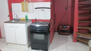 A kitchen with a stove, oven, and sink. - Furnished cabin blocks from the square and downtown Puerto Montt. (Puerto Montt)
