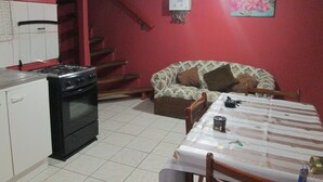A kitchen with a stove, oven, and a dining area with a table and chairs. - Furnished cabin blocks from the square and downtown Puerto Montt. (Puerto Montt)