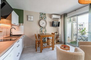 A modern kitchen with a dining area, a TV, and a view of the outside. - Studio with terrace (Avignon)