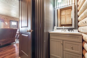 Ein Interieur einer Holzhütte mit Tür, einer Couch, einem Spiegel und einem Waschbecken.