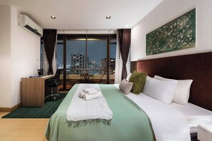 A hotel room with a bed, desk, chair, and a city view through large windows. - KingBed|BTS&Park»5min|ParkView|Gym|Washer|FastWiFi - Apartment (Khlong Toei)
