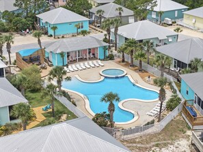 Ein Resort mit großem Swimmingpool, mehreren Liegebereichen und verschiedenen Unterkunftsmöglichkeiten.