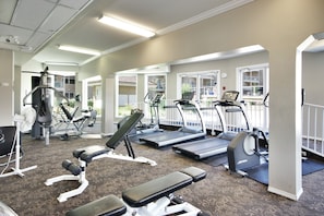 Ein Fitnessstudio mit Laufbändern, Crosstrainern und Gewichtbänken.