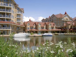Ein Hotel am Wasser mit mehreren Gebäuden, einer Marina voller Boote und einem ruhigen See.