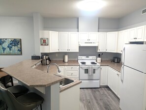 Une cuisine moderne avec des meubles blancs, une cuisinière en acier inoxydable et un plan de travail en granit.