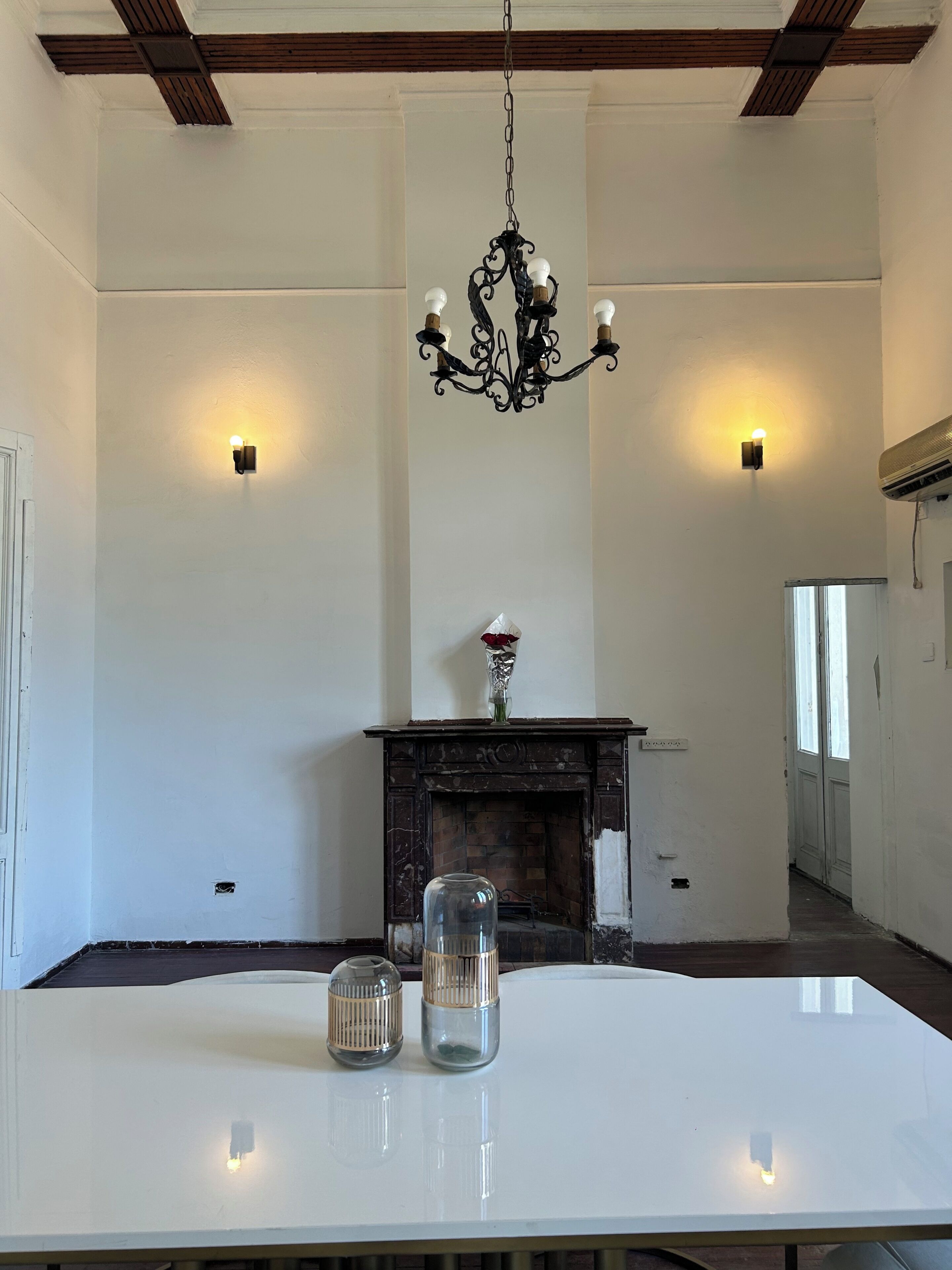 Un comedor con una mesa blanca, una araña negra y una chimenea.