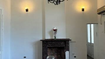 Un comedor con una mesa blanca, una araña negra y una chimenea.