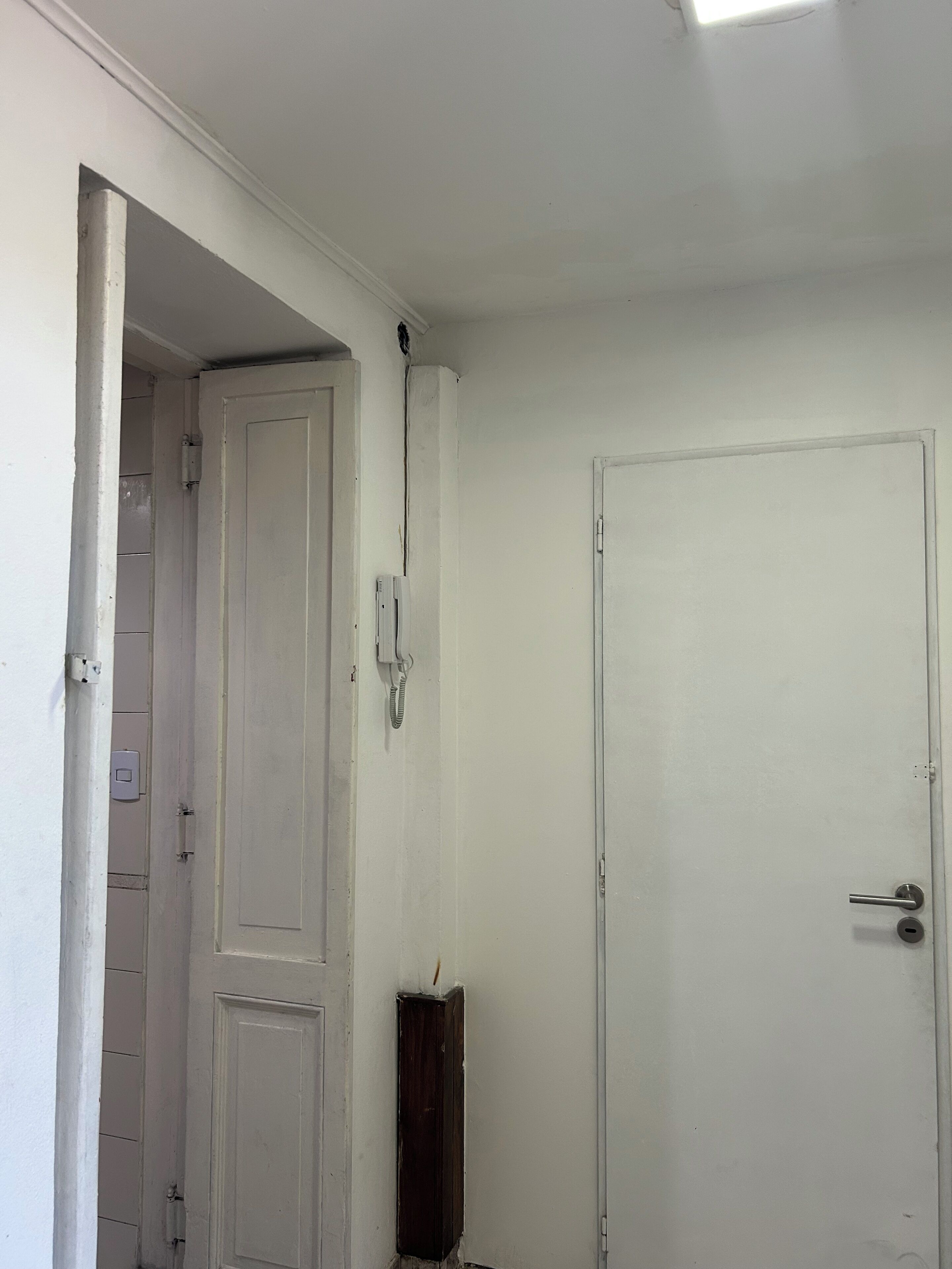 A room with a white door, a white wall, and a partially visible door frame.