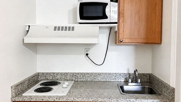Una cocina con microondas blanco, estufa, fregadero y armarios de madera.