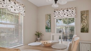 A dining area with a wooden table, white placemats, a bowl, and a potted plant. - Ward Avenue Retreat - the PERFECT location in Ocean Springs. Walk to downtown! (Ocean Springs)