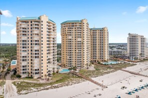A beachfront hotel with multiple high-rise buildings, a sandy beach, and a pool area. - Beach Colony East 2D (Pensacola)