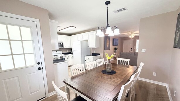 A dining area with a wooden table, white chairs, and a chandelier.