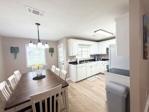 Una cocina moderna con armarios blancos, una mesa de comedor de madera y un horno empotrado.